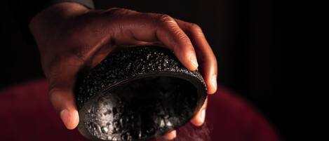 A hand holding a stone over a plate with sushi.