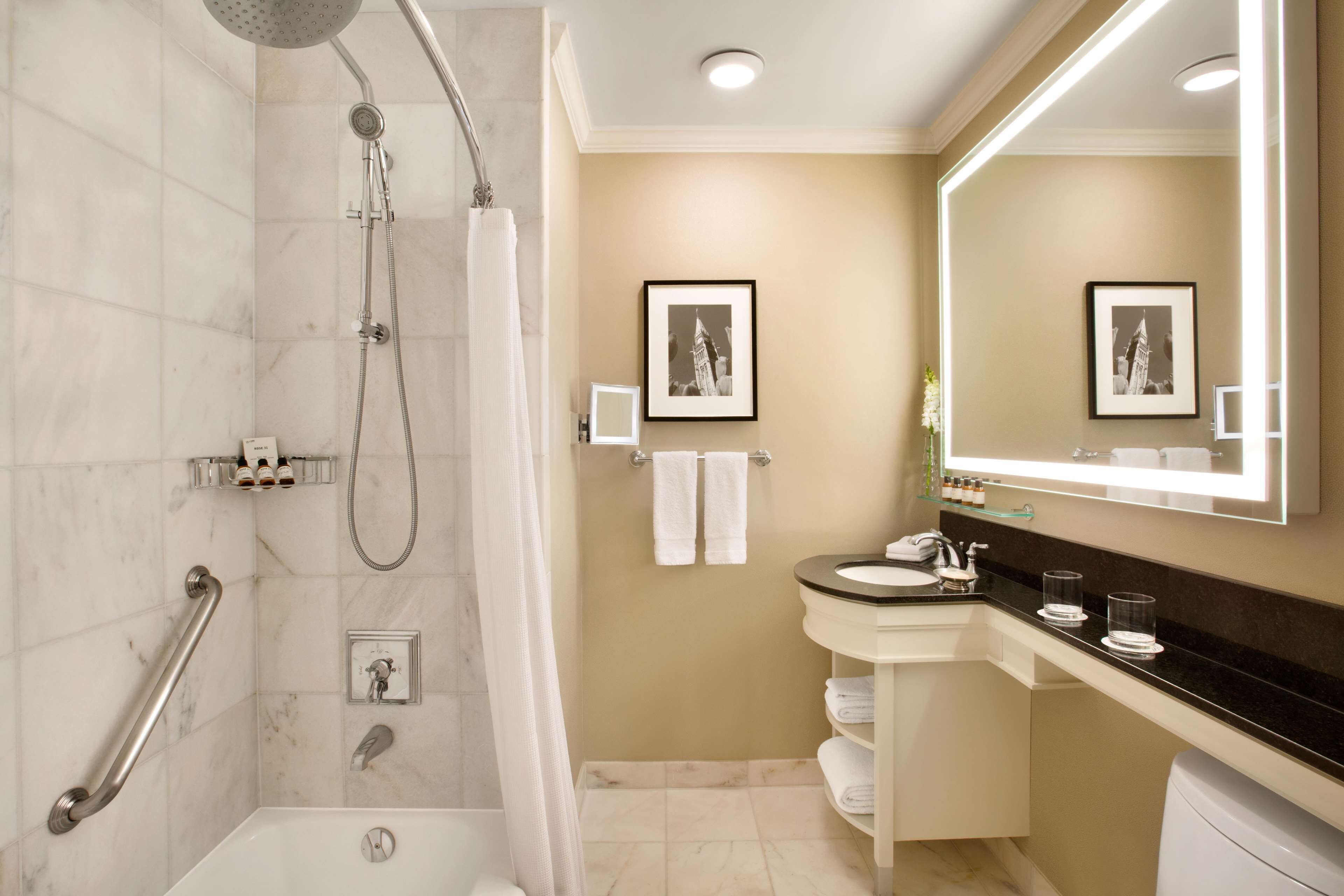 A modern bathroom with a shower, toilet, and sink. There are two framed pictures on the wall.