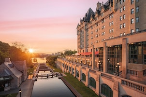 Un edificio histórico con un largo canal en primer plano, ventanas grandes y techo rojo.