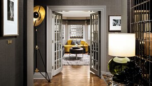 A hallway with a wooden parquet floor, a yellow sofa, a black lamp, and a framed picture on the wall. - Fairmont Chateau Laurier (Ottawa)