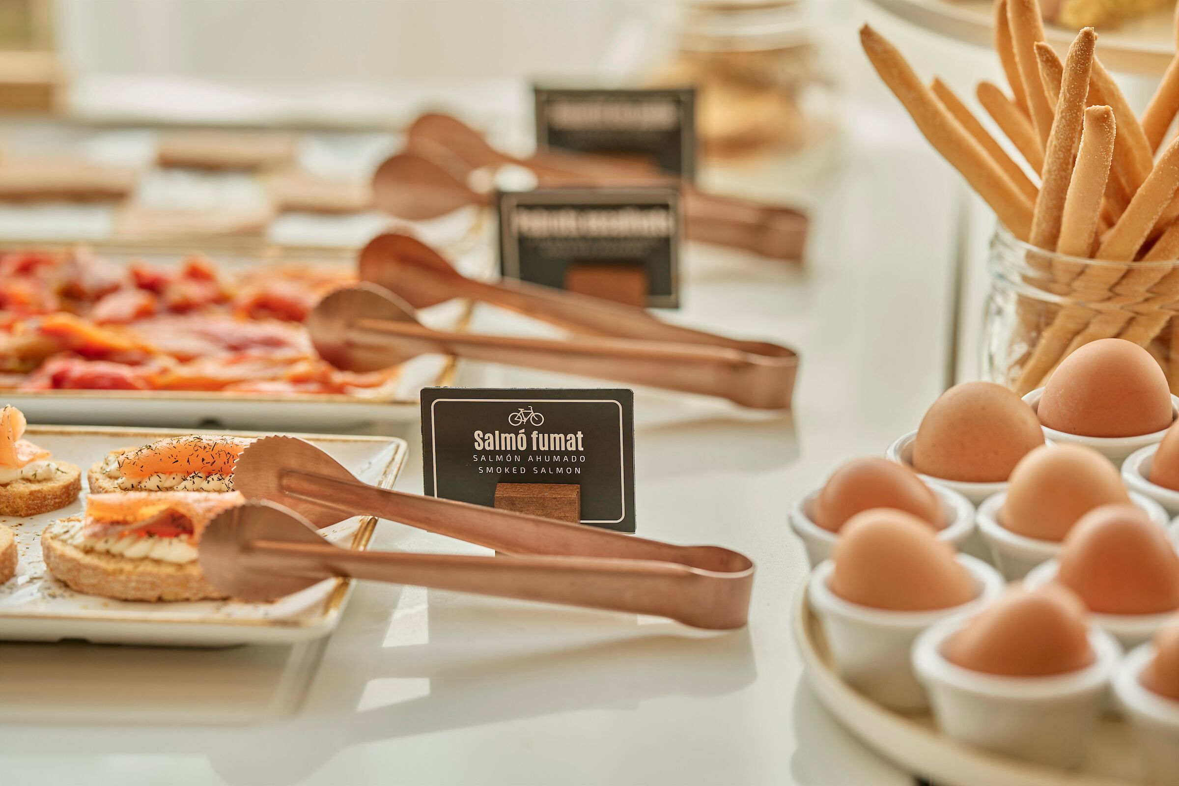 A buffet table with various food items including smoked salmon, eggs, and bread.