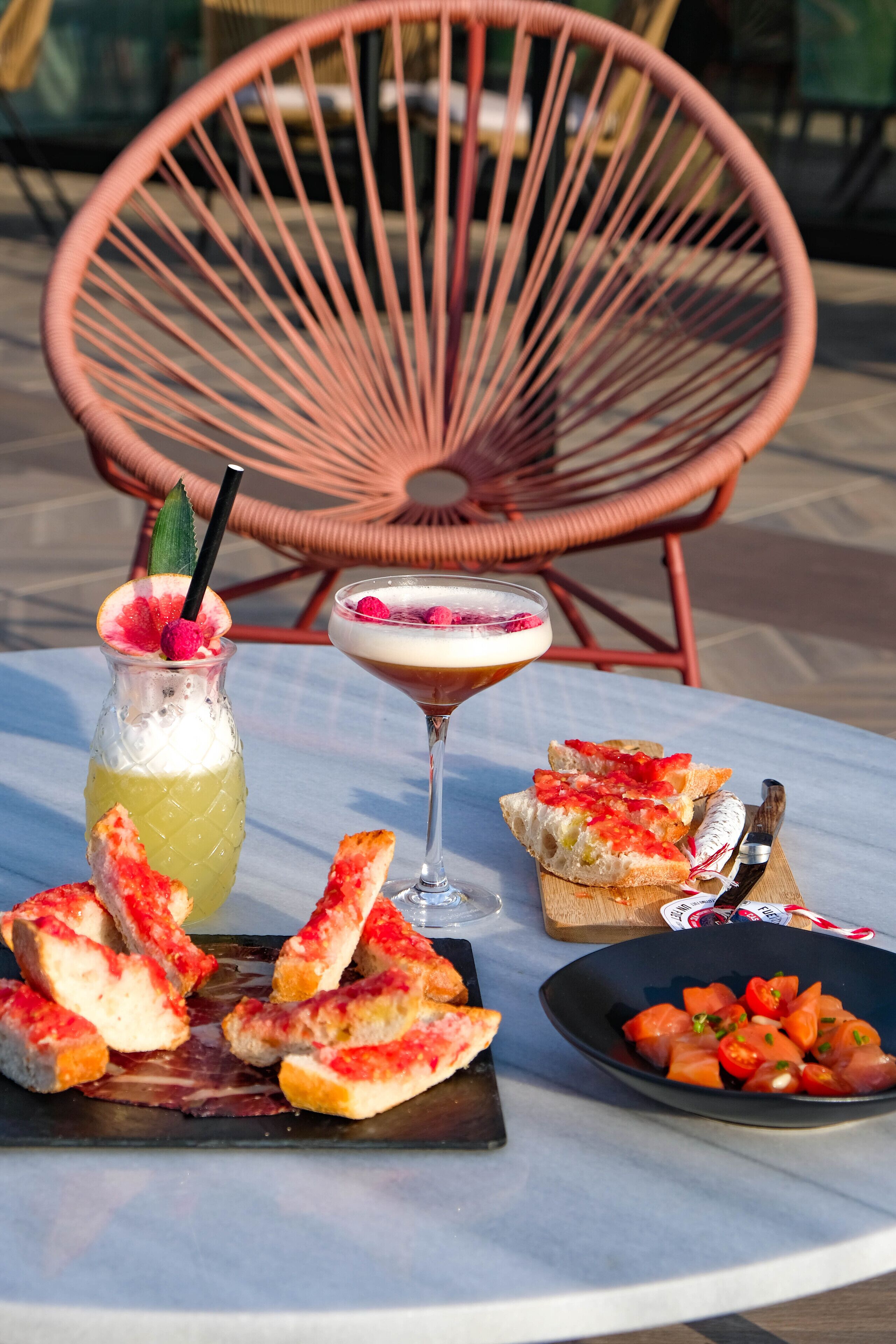 Een tafel met een drankje, een martini en eten, zoals brood en een salade.