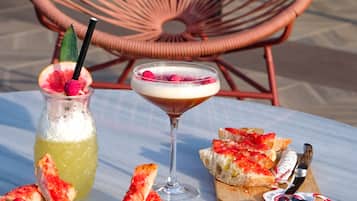 Een tafel met een drankje, een martini en eten, zoals brood en een salade.