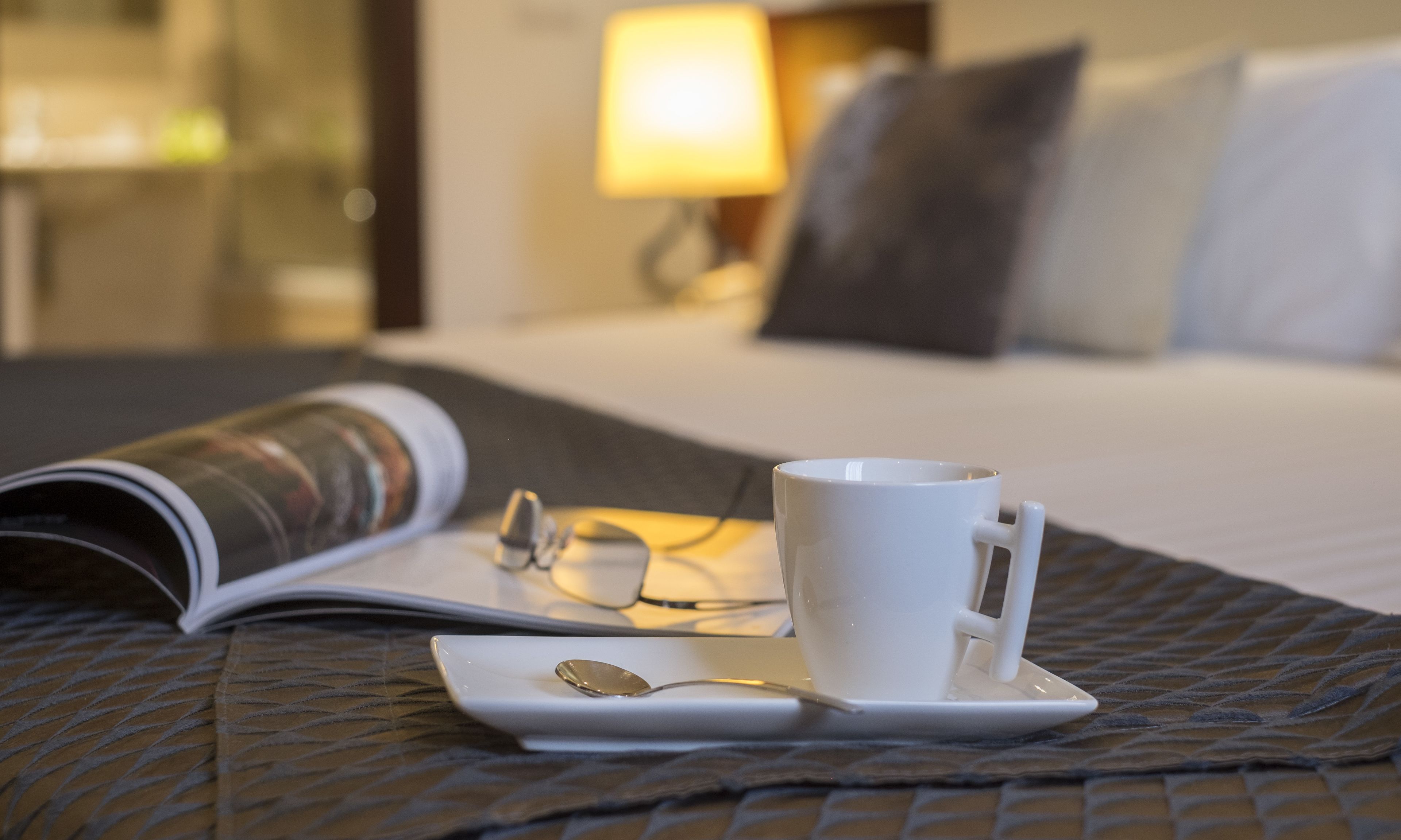A neatly made bed with a white comforter, a white pillow, and a white pillow on a headboard.