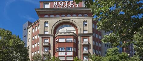 Un hôtel au style architectural classique, caractérisé par une entrée en arc imposante et de nombreux balcons.