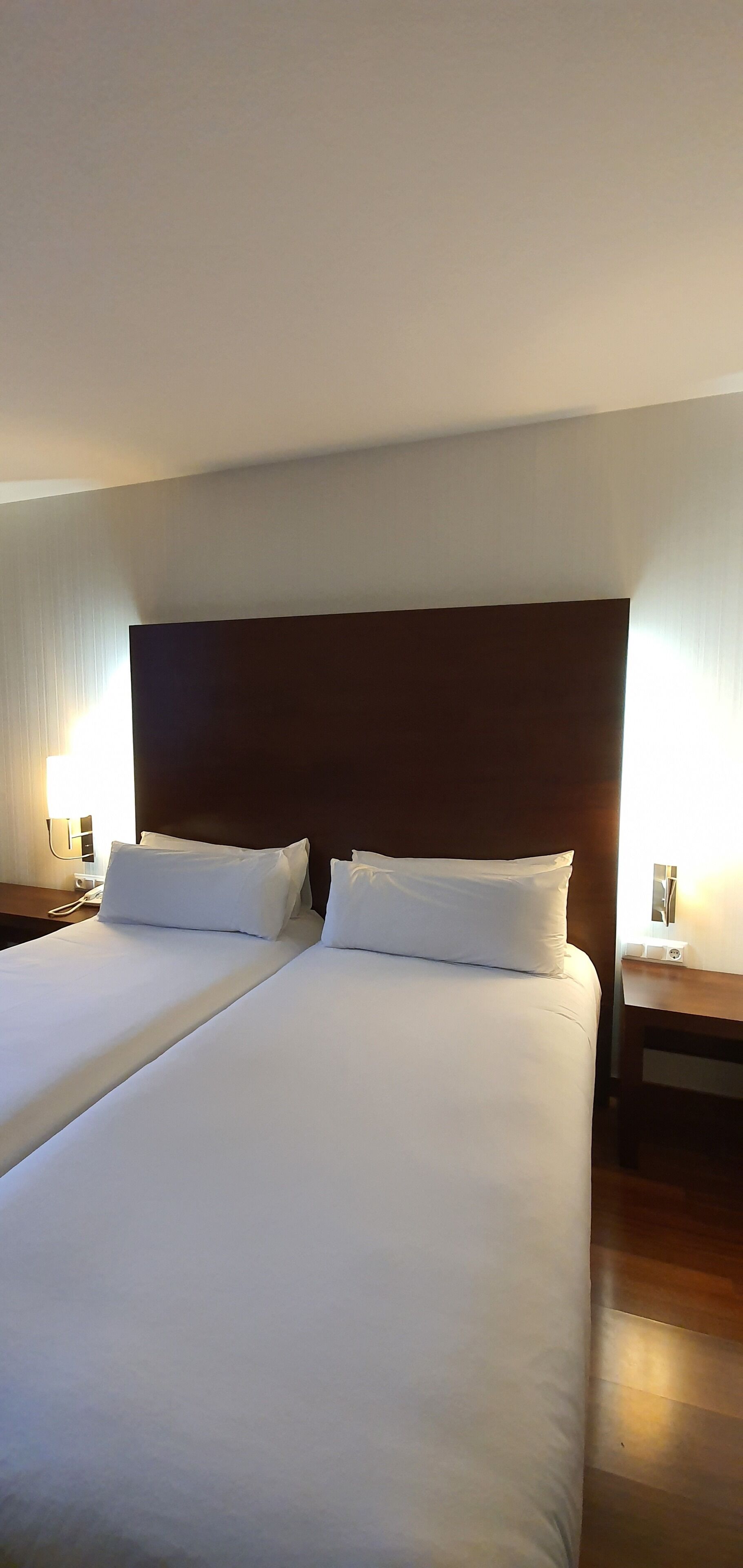 Cama doble con sábanas blancas en una habitación de hotel.