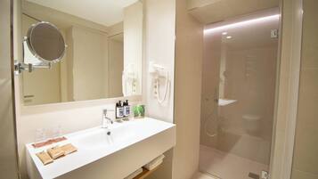 Een moderne badkamer met een witte wastafel, spiegel en een douche met glazen wanden.