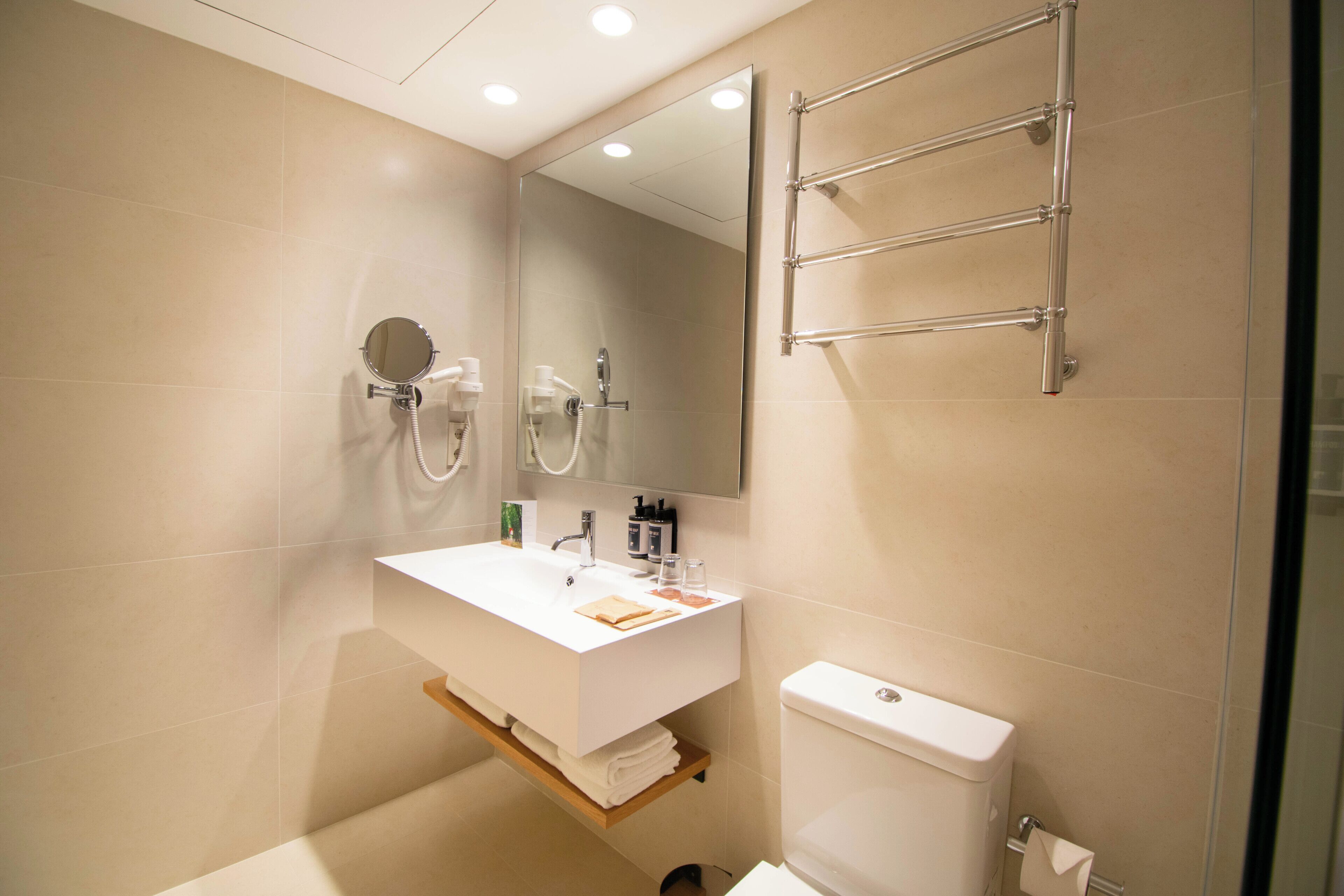 A modern bathroom with a white sink, mirror, and towel rack.