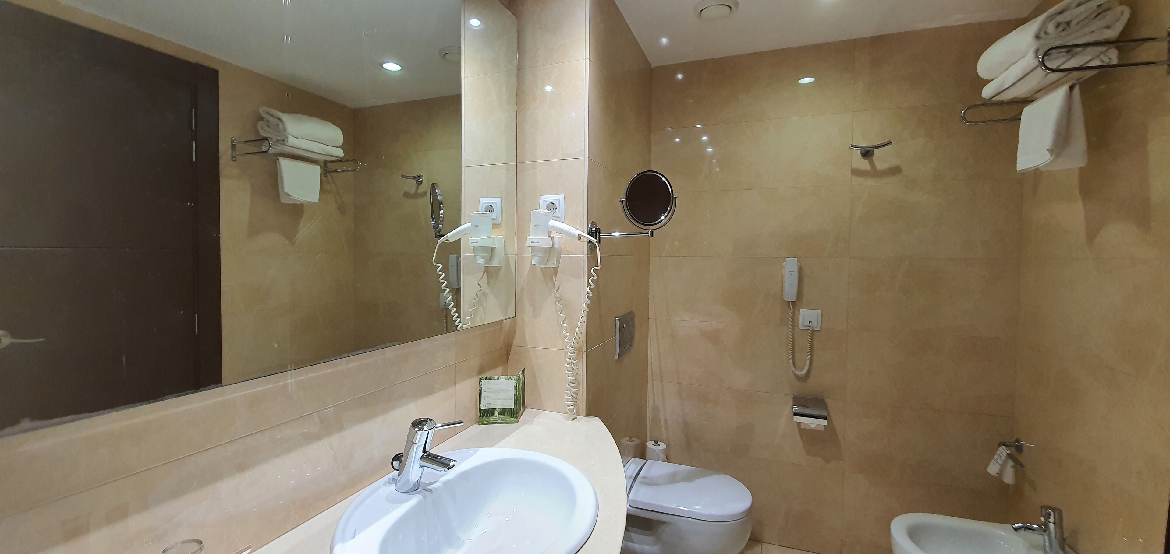 A modern bathroom with a large mirror, a sink, a toilet, and a shower area.