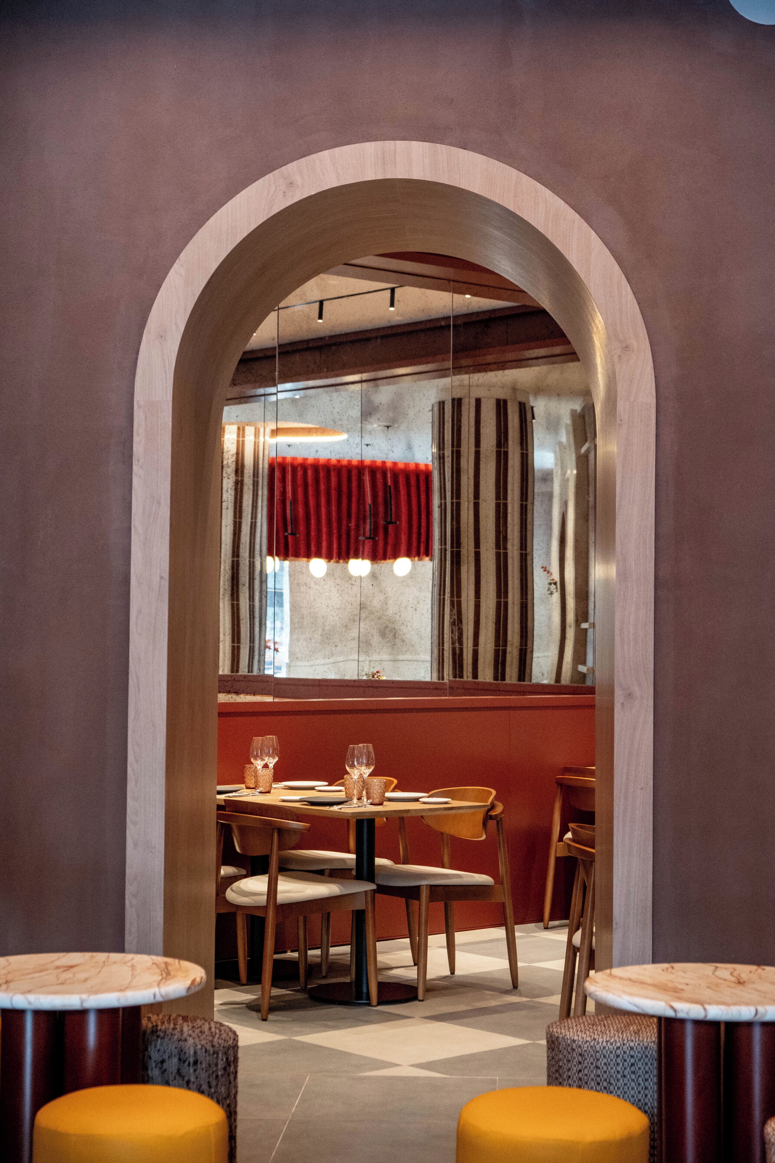 Interior de restaurante com área de jantar central, mesas e cadeiras de madeira.
