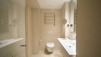 Een moderne badkamer met een douchecabine van glas, toilet, wastafel met spiegel en een handdoekrek.