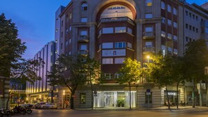 Un hotel con una entrada arqueada destacada, varios balcones y un letrero que indica que es un hotel.