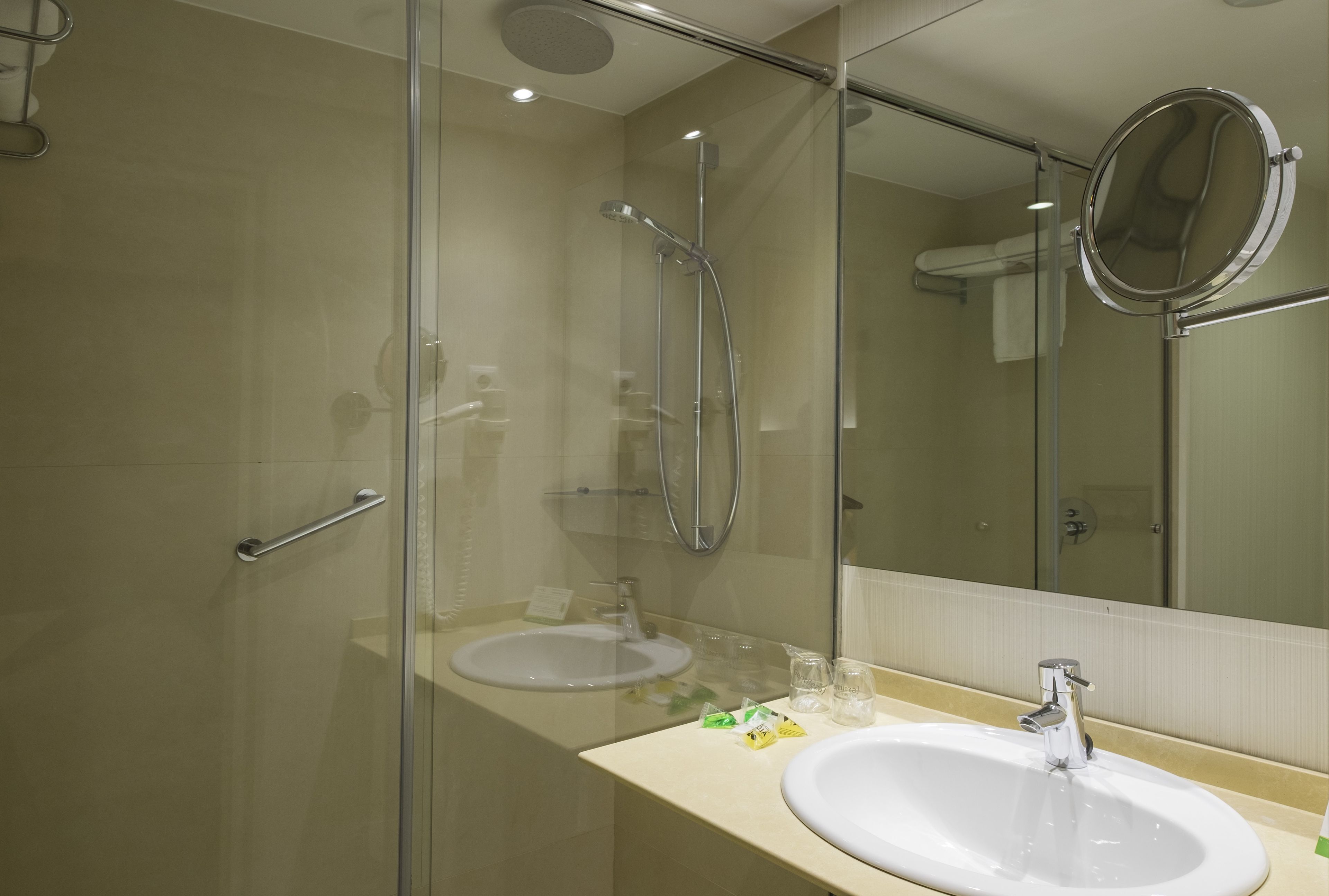Un baño moderno con ducha de vidrio, lavamanos y espejo.