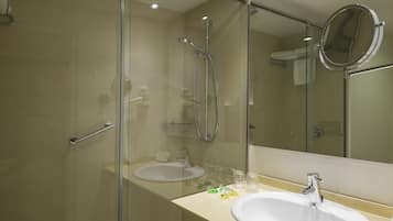 Un baño moderno con ducha de vidrio, lavamanos y espejo.