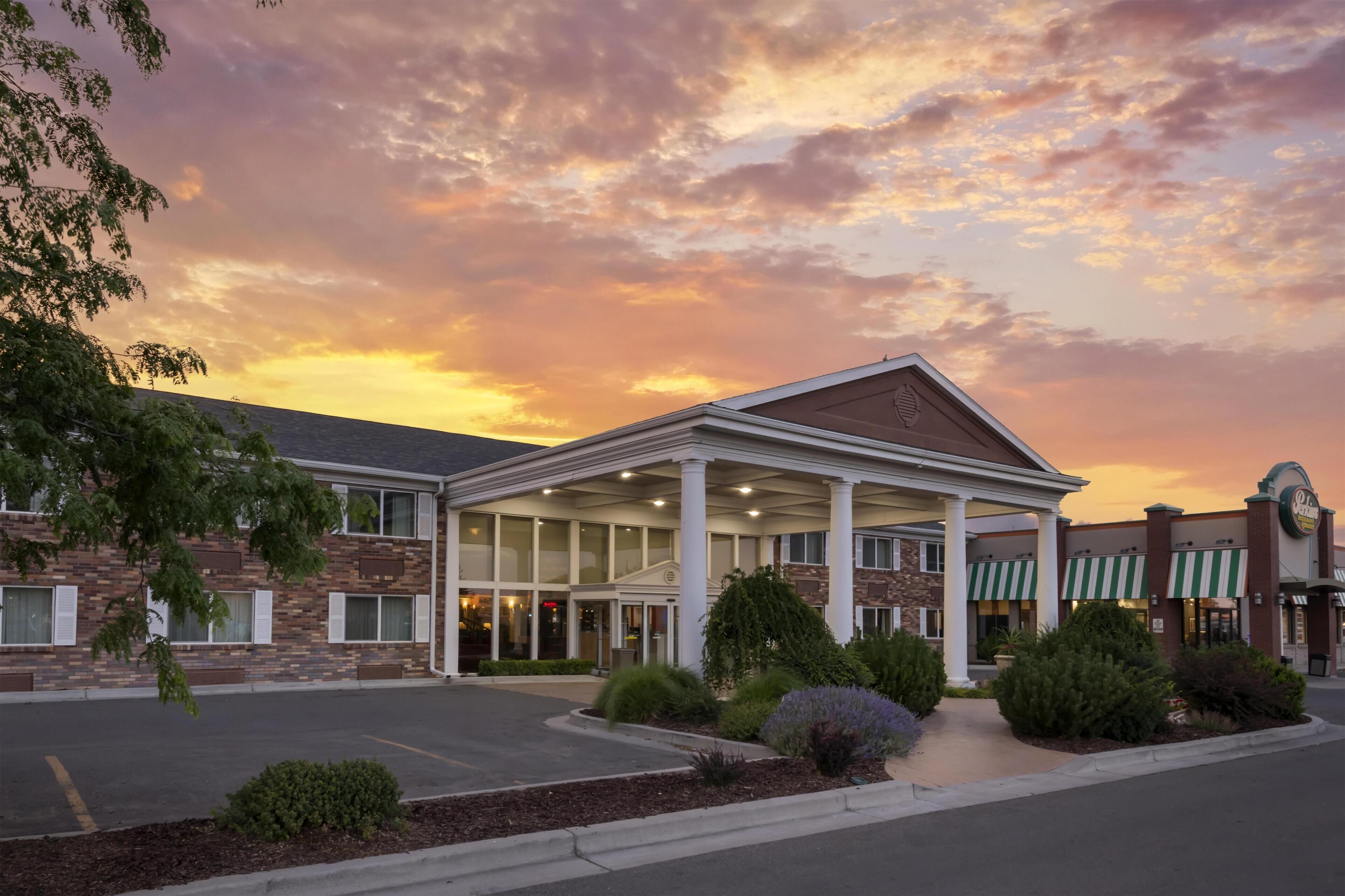 A hotel with a covered entrance, brick facade, and a parking lot.