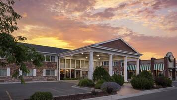 A hotel with a covered entrance, brick facade, and a parking lot.