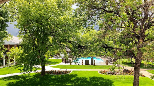 A well-maintained lawn with a swimming pool, surrounded by trees and a brick building. - Best Western Plus Burley Inn & Convention Center (Burley)
