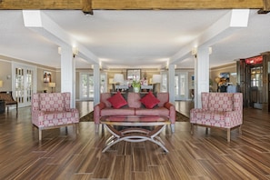 A spacious lobby with a central red patterned sofa, two matching armchairs, and a glass coffee table. - Best Western Plus Burley Inn & Convention Center (Burley)