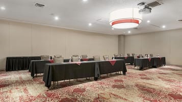 A conference room with multiple tables, chairs, and a carpeted floor.
