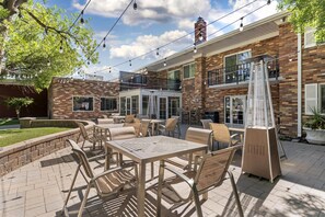 An outdoor patio with tables and chairs, a brick building with a balcony, and a signboard. - Best Western Plus Burley Inn & Convention Center (Burley)