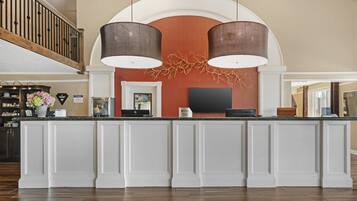 A hotel reception area with a marble counter, two pendant lights, a flat-screen TV, and a decorative wall piece.