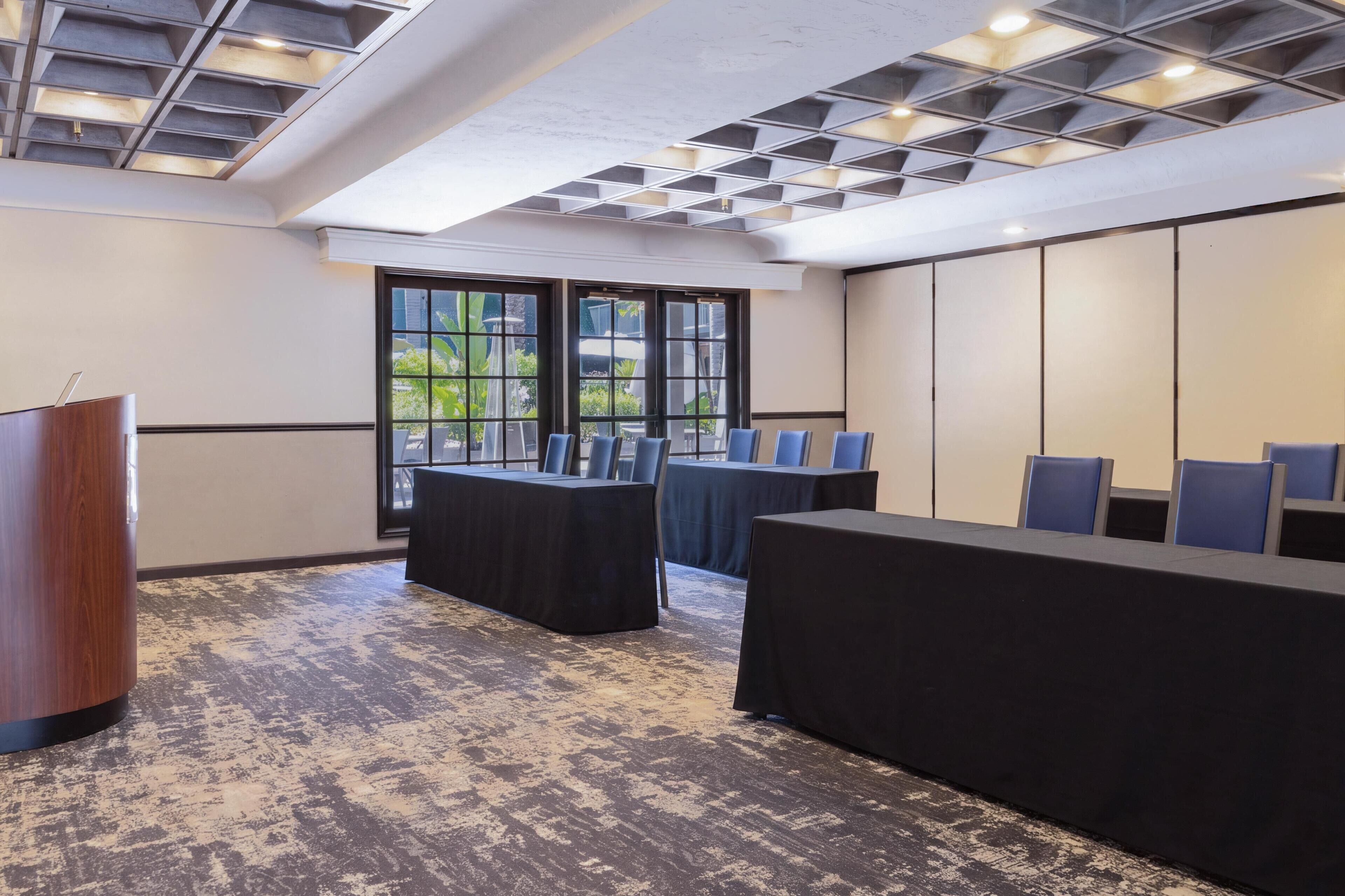 Une salle de conférence avec une longue table, des chaises et un pupitre.
