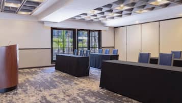 Une salle de conférence avec une longue table, des chaises et un pupitre.