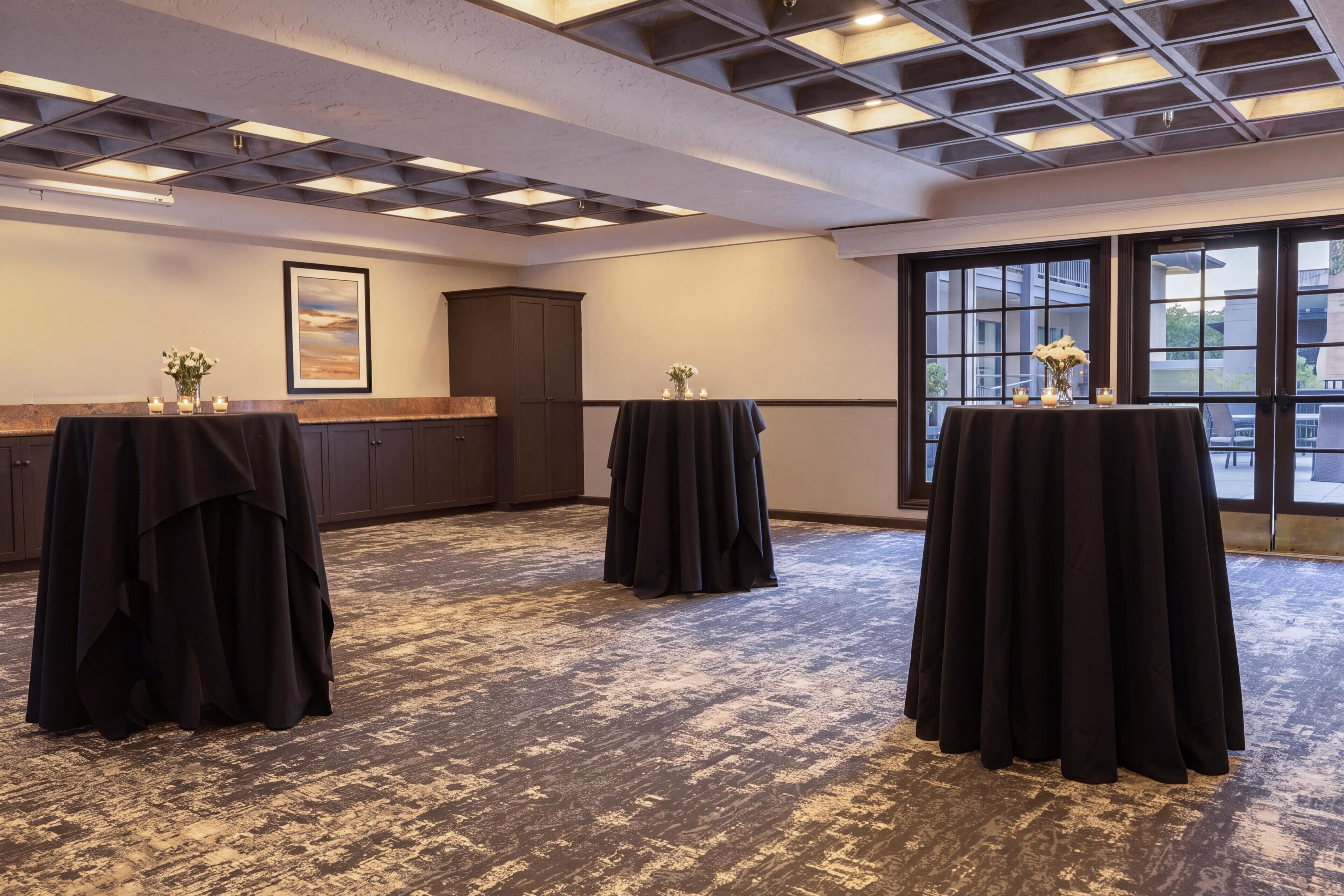 A conference room with tables, a large window, and a ceiling with recessed lighting.
