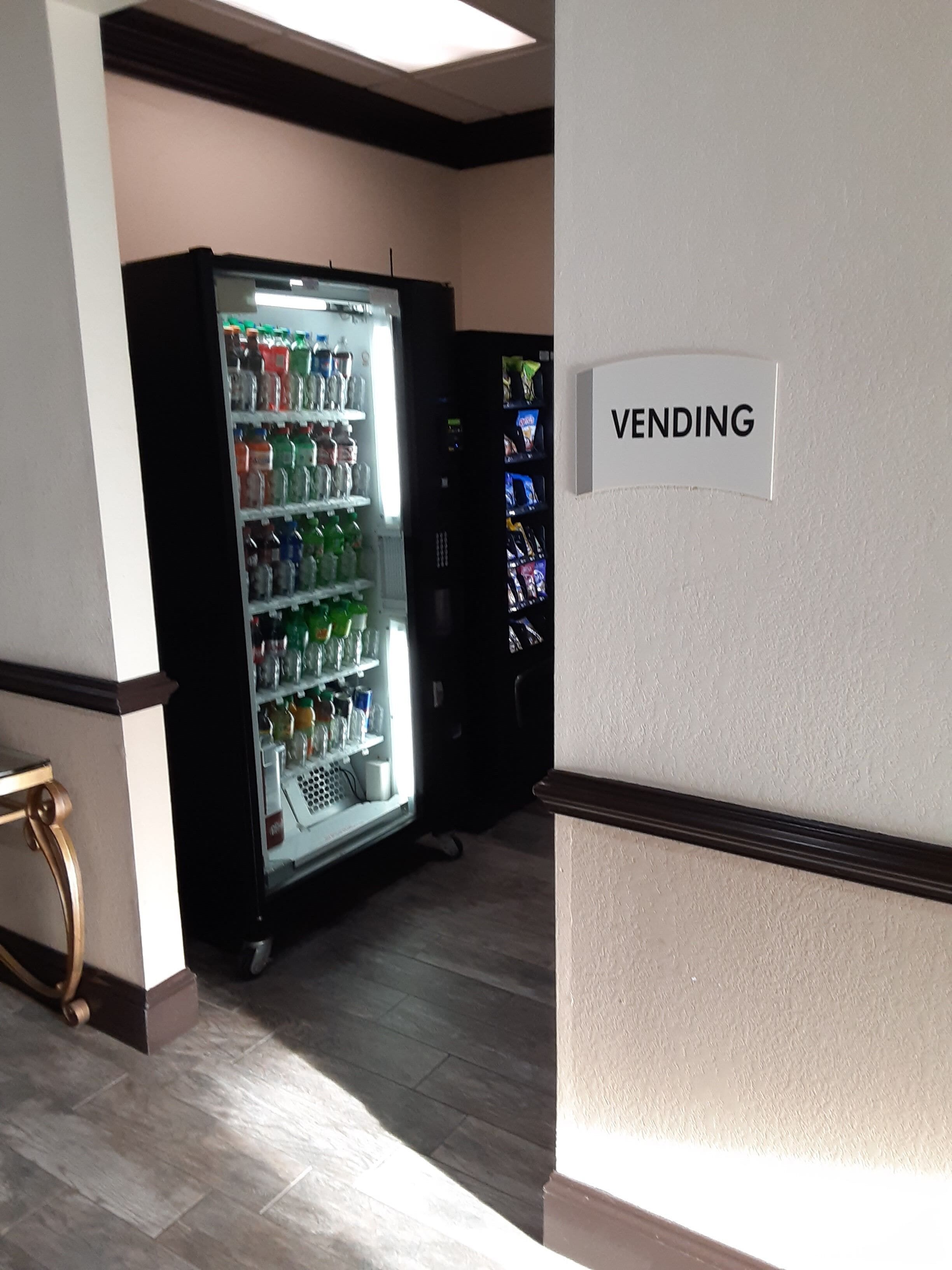 A vending area with a sign labeled "VENDING" and a refrigerator stocked with beverages.