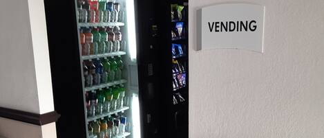 A vending area with a sign labeled "VENDING" and a refrigerator stocked with beverages.
