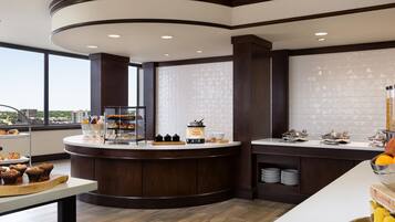 A modern kitchen with a central island, a breakfast bar, and a view of the city.