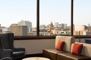 A hotel room with a large window, a sofa, a chair, and a lamp. - Hilton Garden Inn Austin Downtown (Austin)