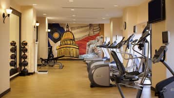 A gym with exercise equipment, a wall mural, and a basketball hoop.