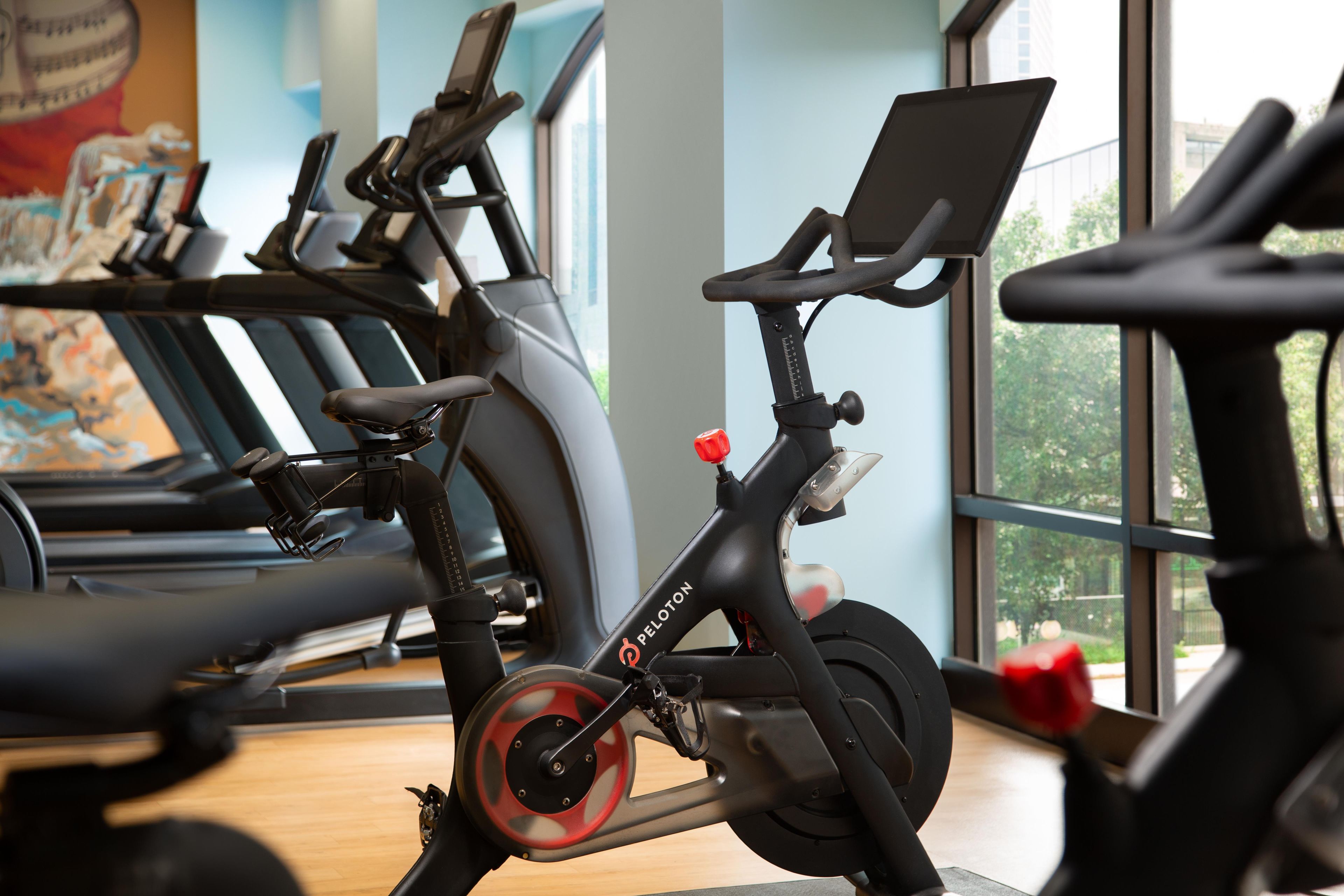 An indoor gym with stationary bikes, a treadmill, and a large window providing a view of the outdoors.