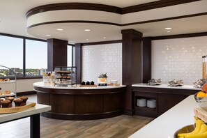 A modern kitchen with a central island, a breakfast bar, and a view of the city. - Hilton Garden Inn Austin Downtown (Austin)