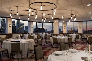 A dining area with round tables, chairs, and a city view. - Hilton Garden Inn Austin Downtown (Austin)