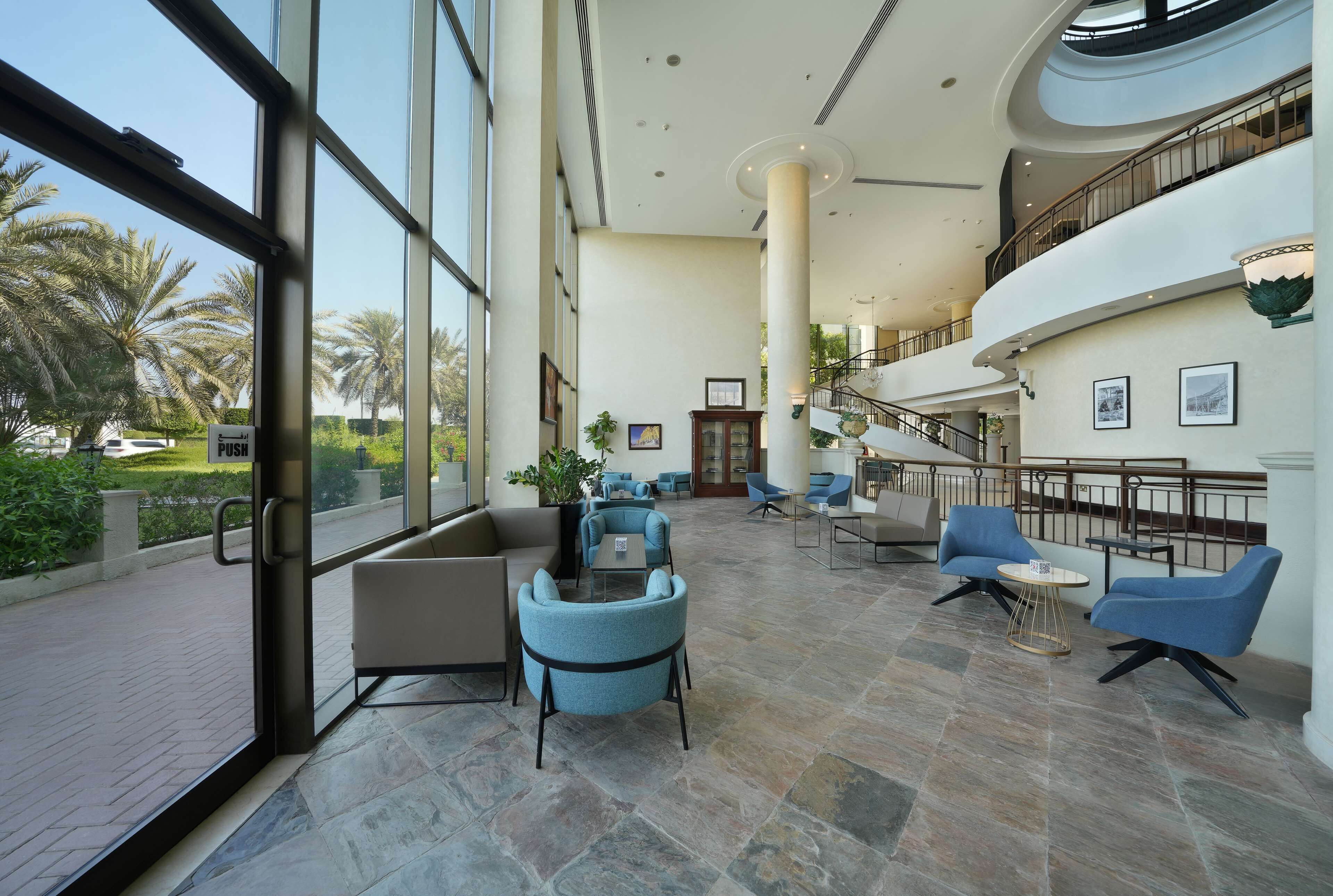 A spacious lobby with large windows, a central column, and seating areas.