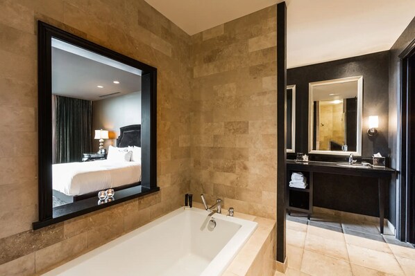 A modern bathroom with a large bathtub, a vanity with a mirror, and a shower area.
