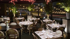 A restaurant with tables set for dining, surrounded by wicker chairs and potted plants. - Hotel Zaza Houston Museum District (Houston)