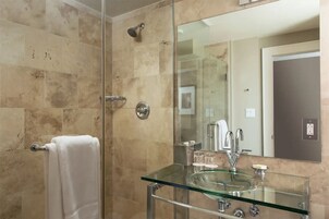 Un bagno moderno con cabina doccia in vetro, lavabo in vetro e uno specchio grande.