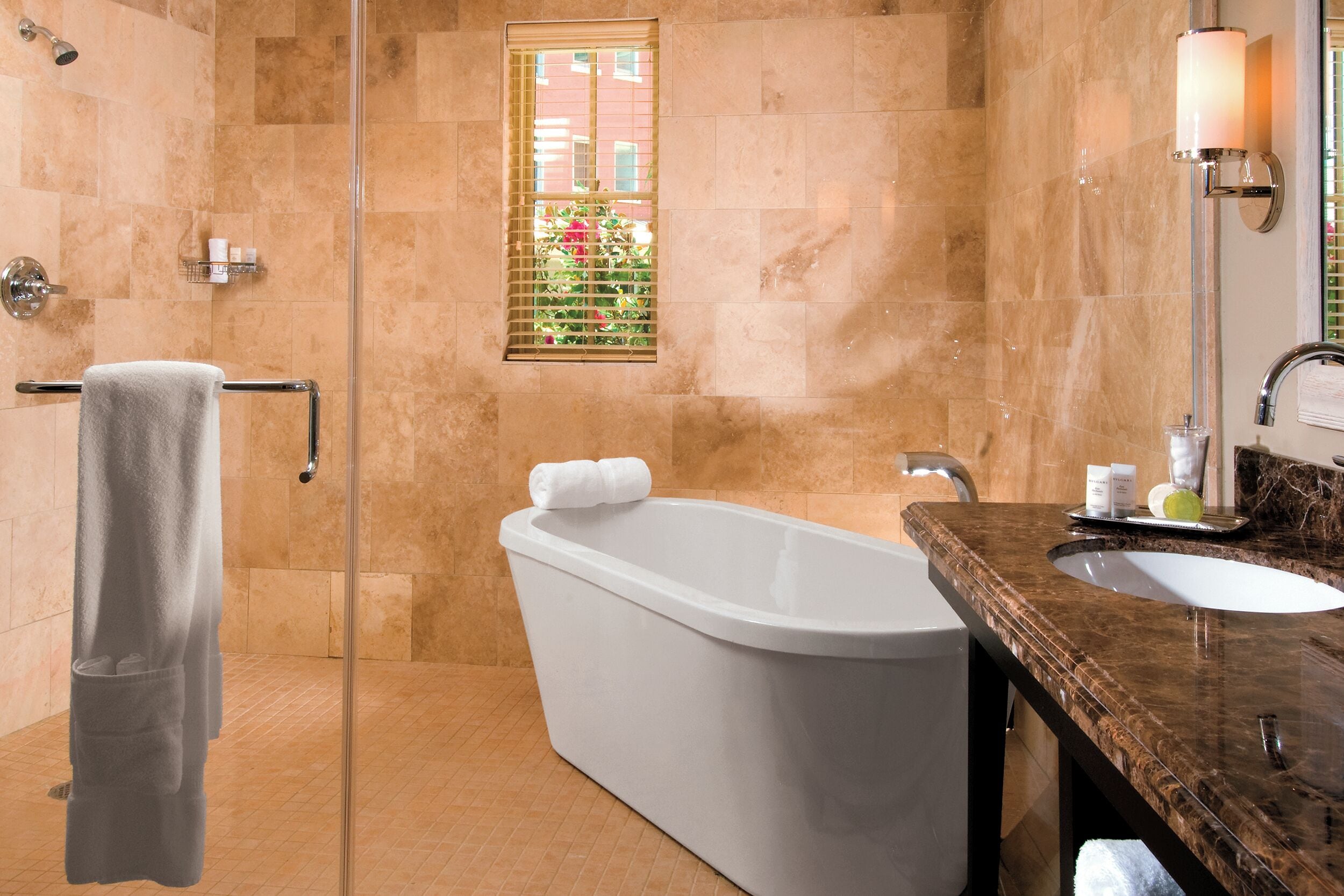 A bathroom with a bathtub, a sink, a glass shower enclosure, and a towel rack.