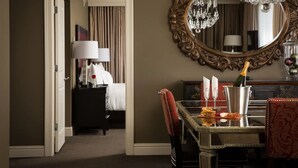 A hotel room with a bed, a nightstand, a desk with a chair, a large mirror, and a chandelier. - Hotel Zaza Houston Museum District (Houston)