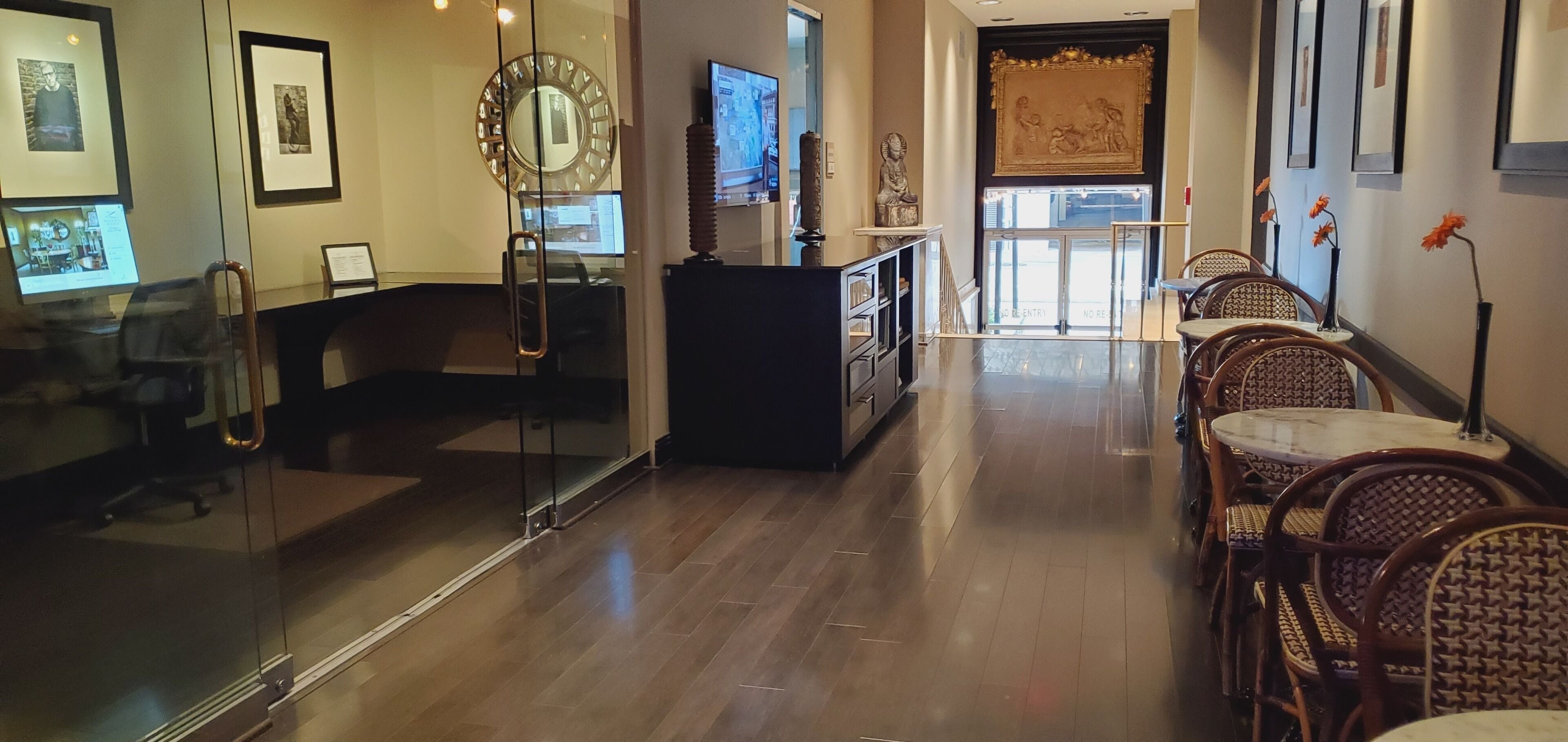 A hotel lobby with a reception desk, seating area, and artwork on the walls.