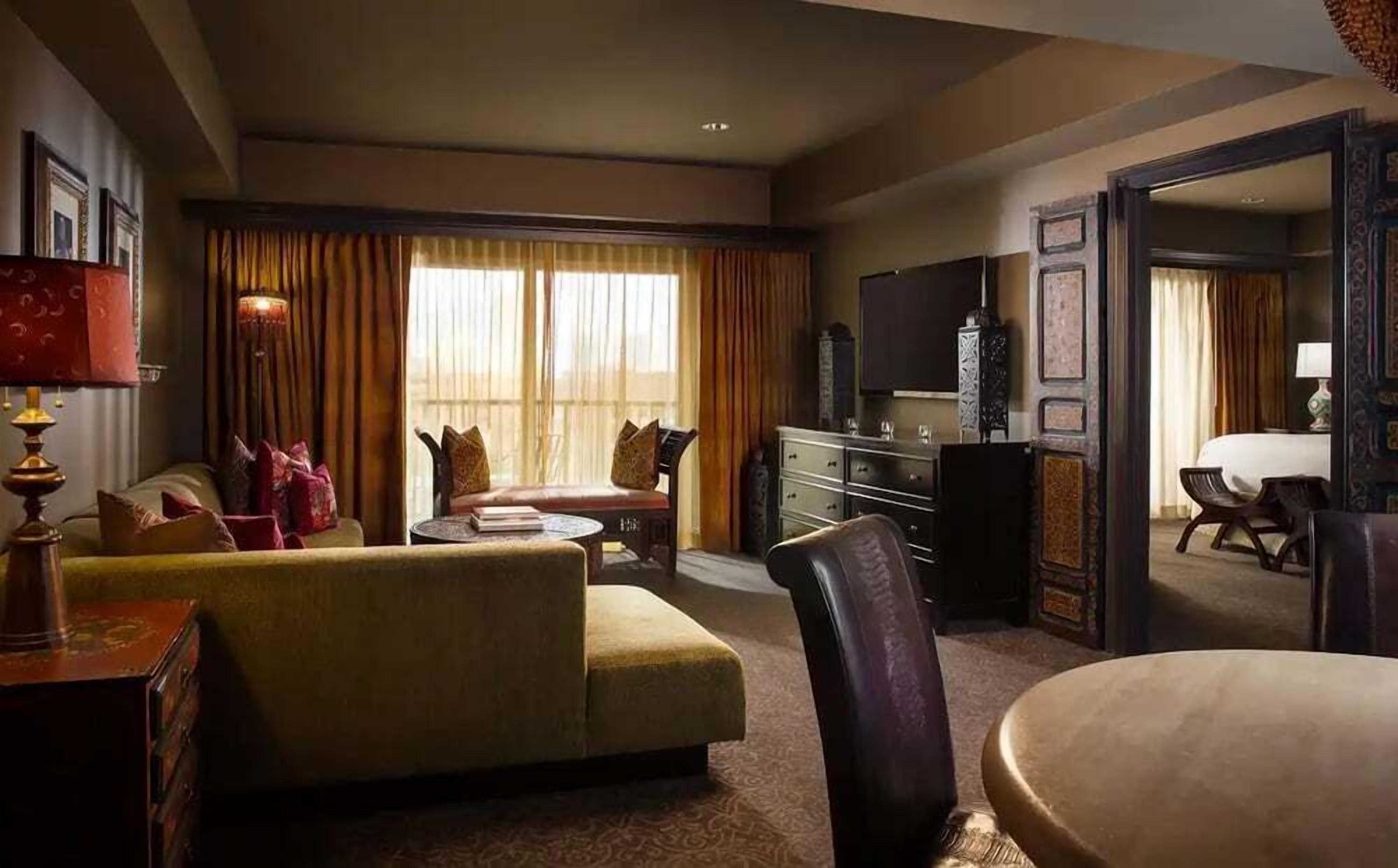 A hotel room with a sofa, a chair, a television, and a desk.