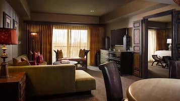 A hotel room with a sofa, a chair, a television, and a desk.