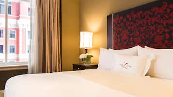 Habitación de hotel con una cama grande, una mesita de noche con lámpara y flores, y una decoración de pared.