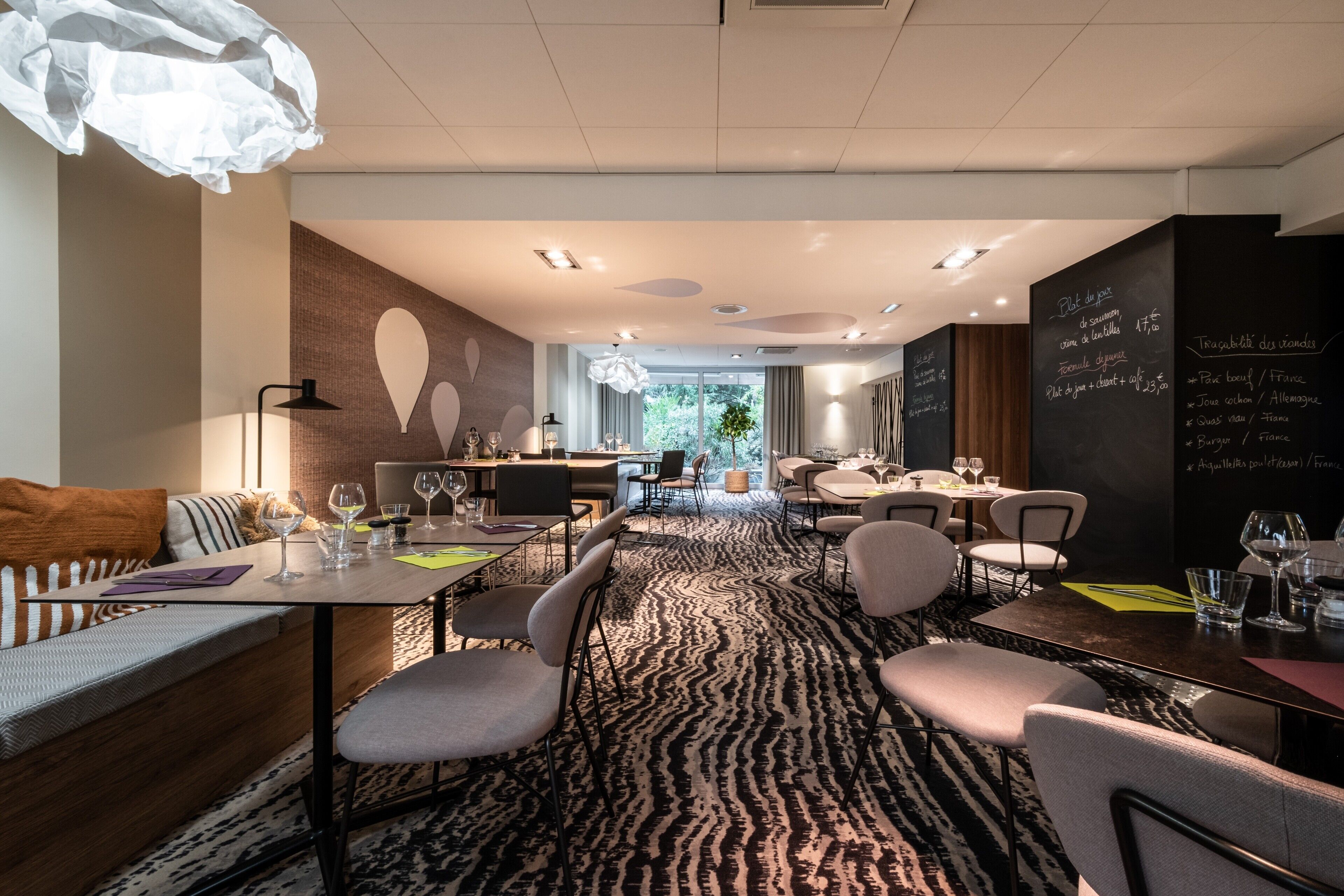 Un espace repas moderne, avec des tables, des chaises et un tapis à motifs.