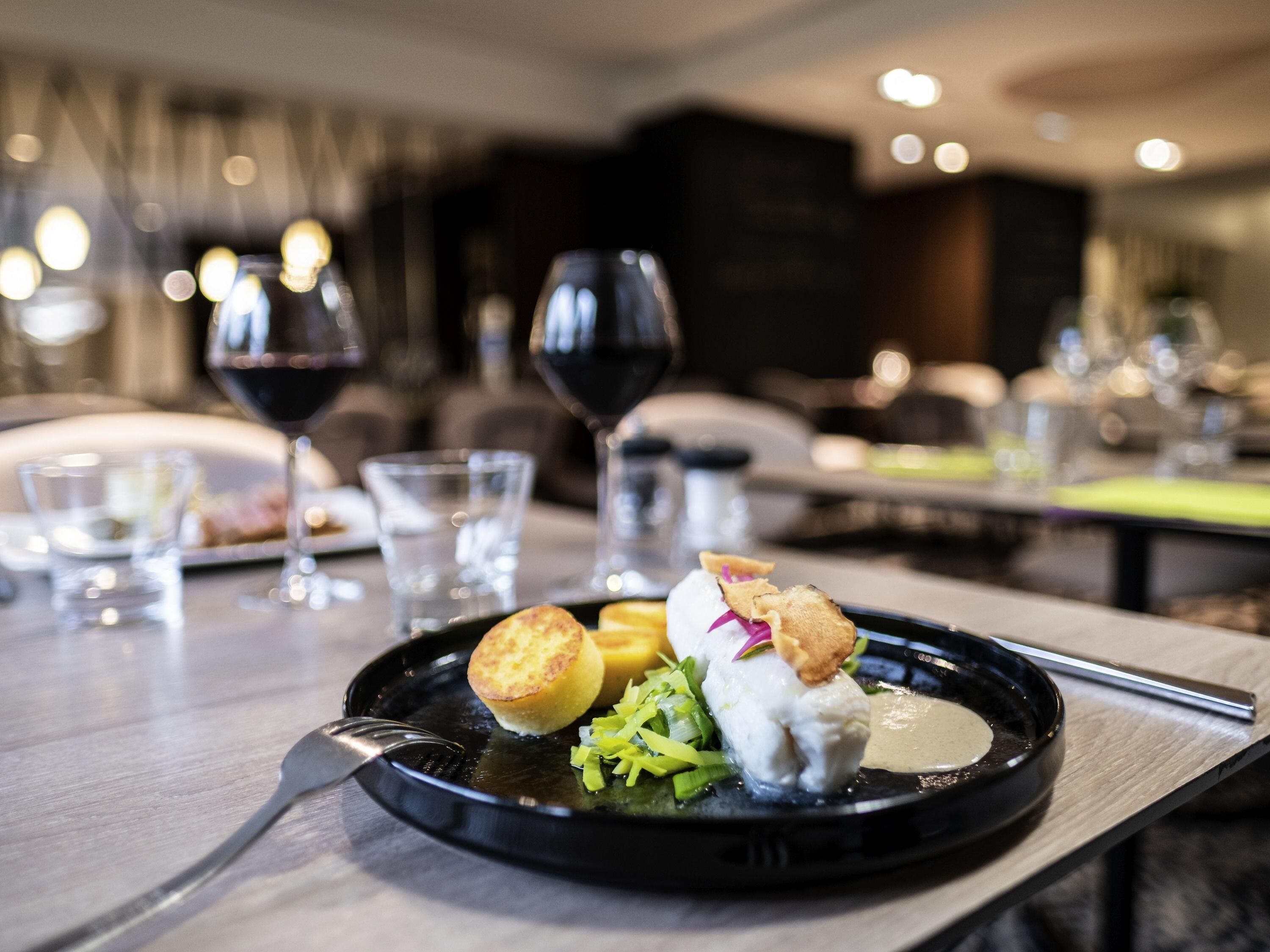 Una mesa de comedor con un plato de comida, copas de vino y cubiertos.