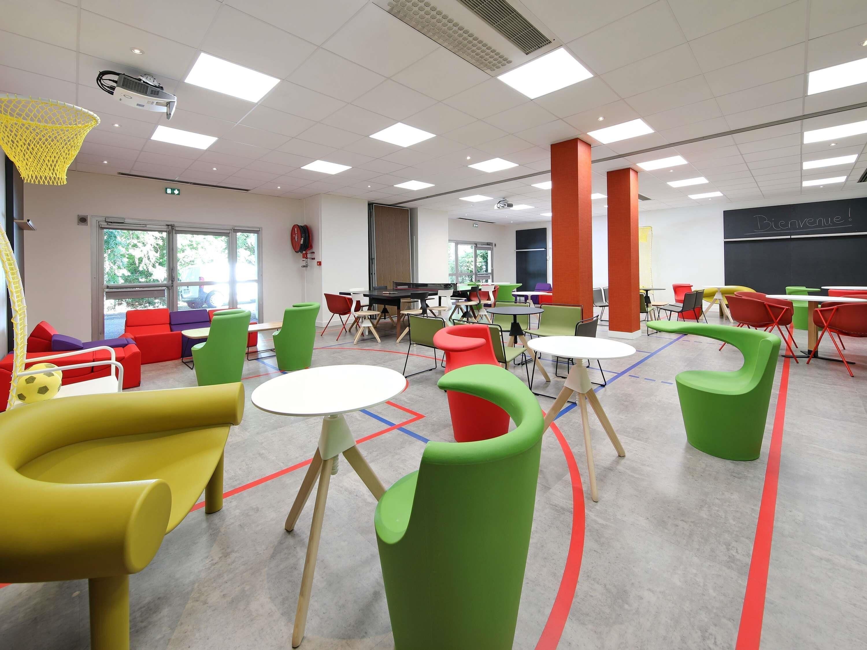 A modern classroom with colorful chairs, tables, and a projector.