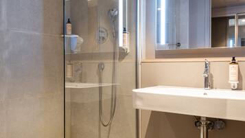Une salle de bain moderne avec une douche à parois de verre, un lavabo blanc et un miroir au-dessus.
